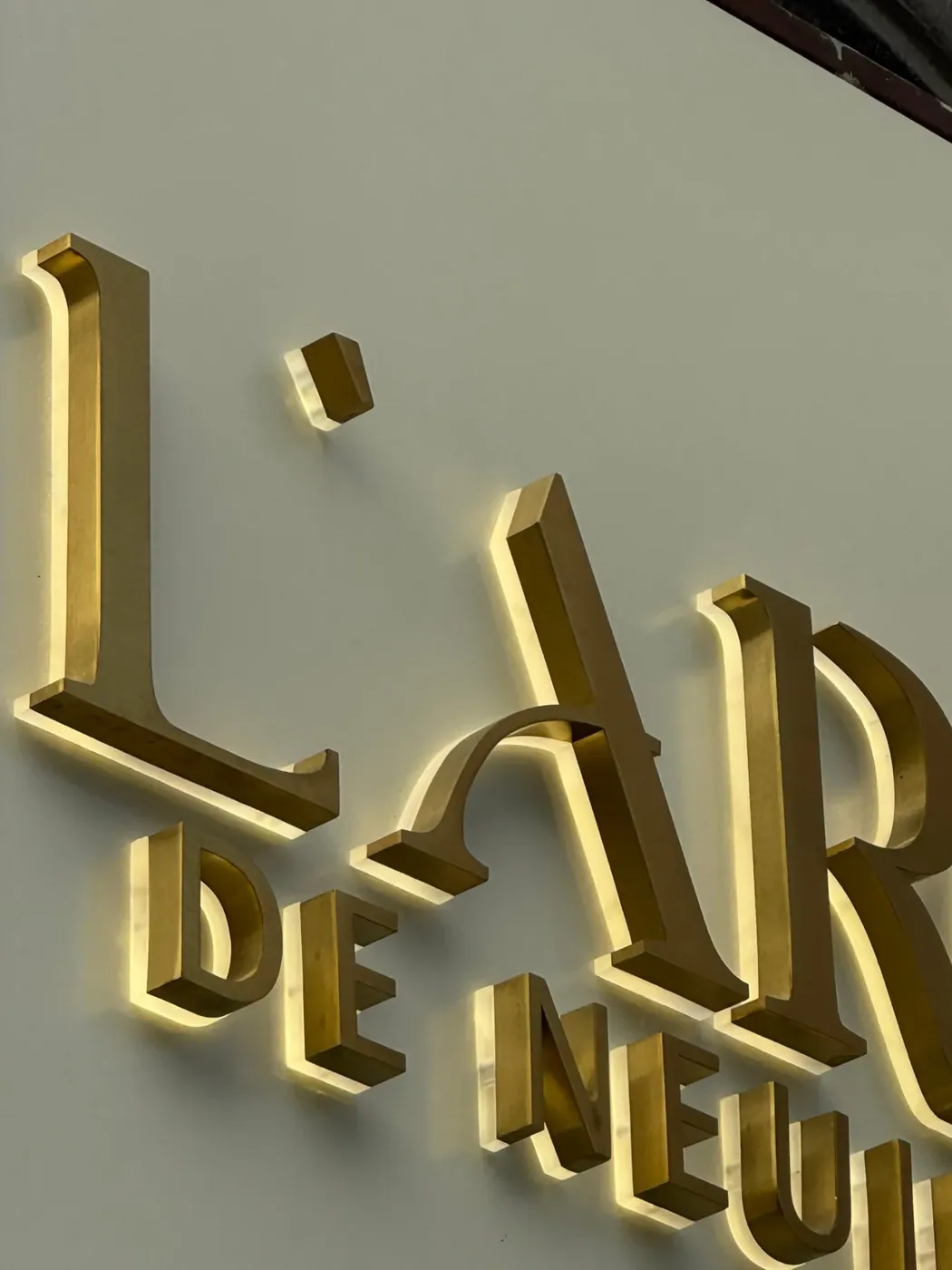 Lettres lumineuses en laiton brossé rétroéclairées de L’Arc de Neuilly, par LADONNA