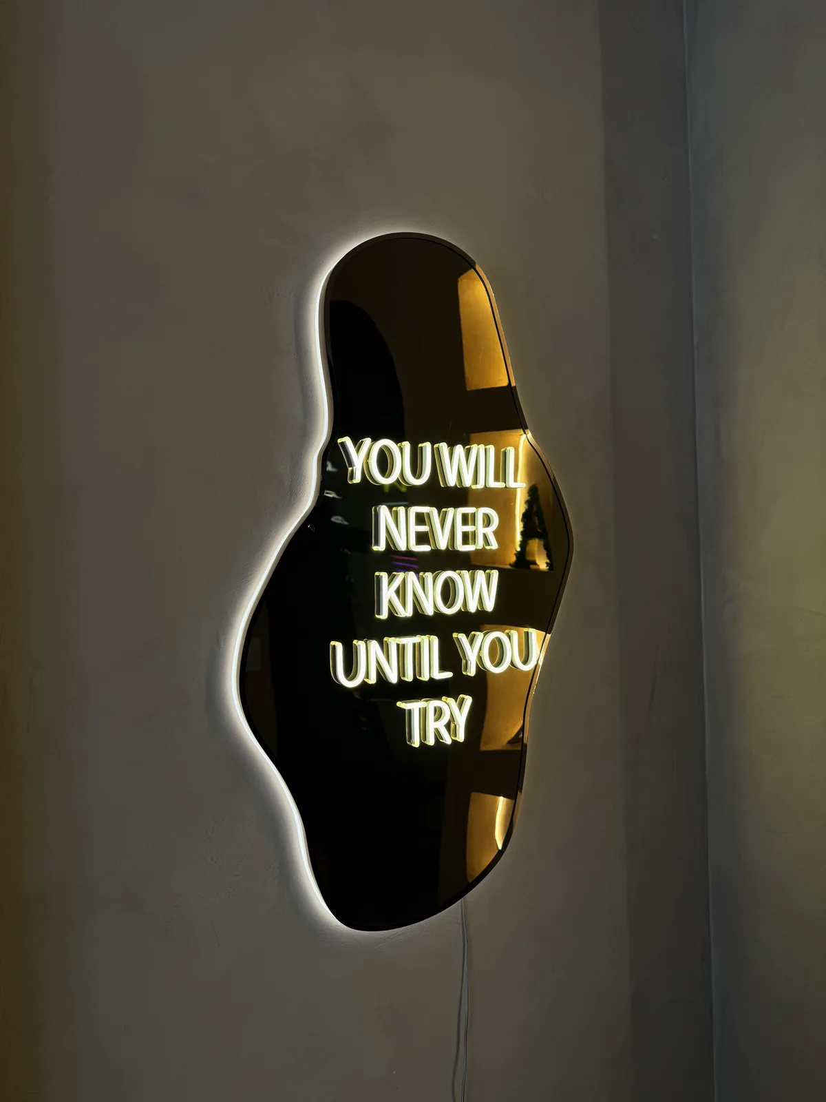 Néon blanc sur miroir noir découpé et rétroéclairé, phrase You will never know until you try, showroom de Ris-Orangis, par LADONNA