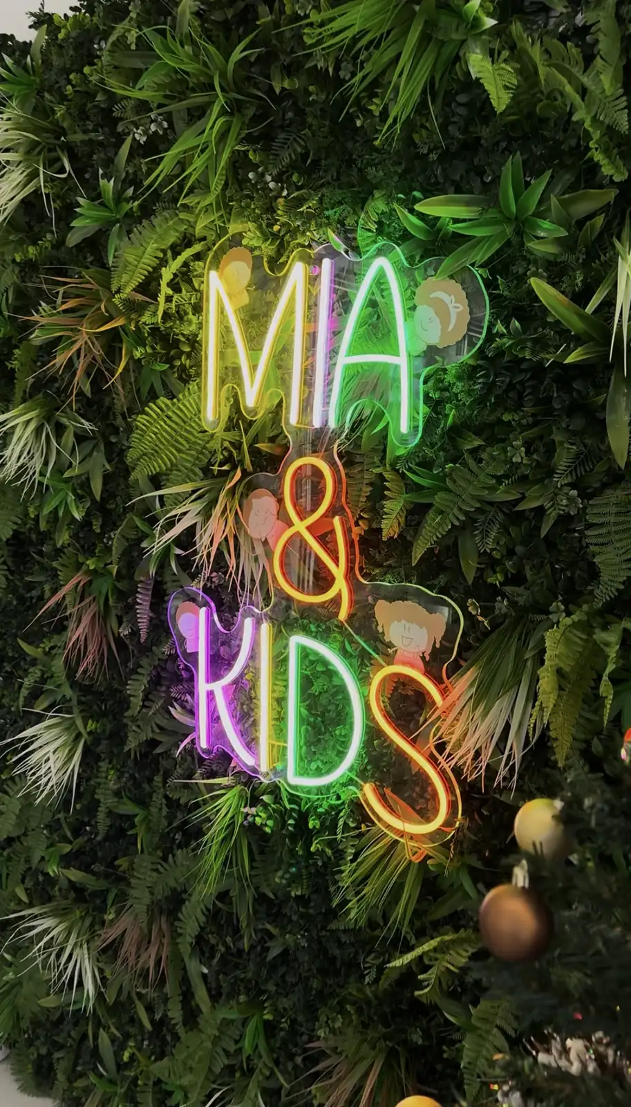 Néon multicolore Mia & Kids sur un mur végétal, Vaires-sur-Marne, par LADONNA