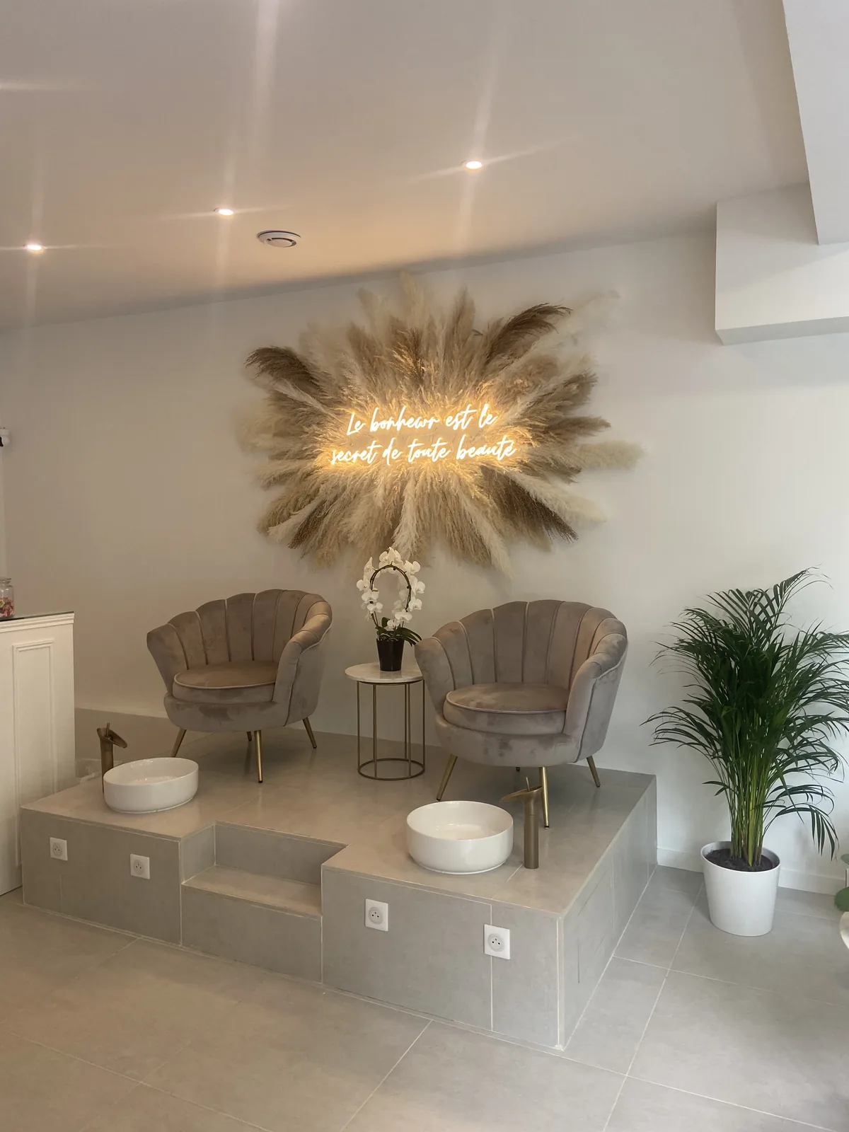 Phrase en néon doré sur une couronne de pampas au-dessus des fauteuils de beauté du Majestic à Villemomble, par LADONNA