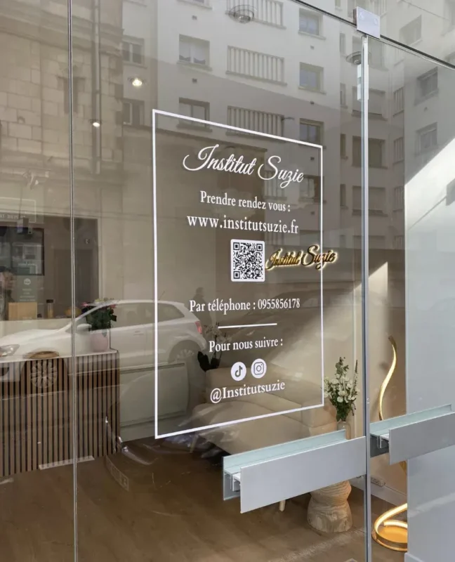 Logo, horaires et QR code en lettrage blanc sur la porte vitrée de L’institut Suzie à Nantes, par LADONNA