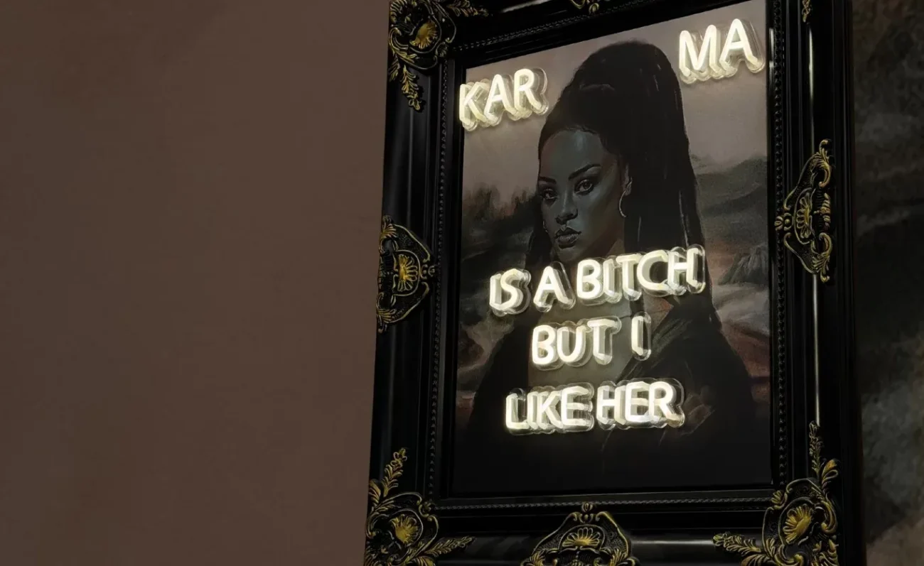 Tableau néon Karma : portrait dans un cadre baroque noir et or, phrase en lettres lumineuses blanches, showroom de Ris-Orangis, par LADONNA